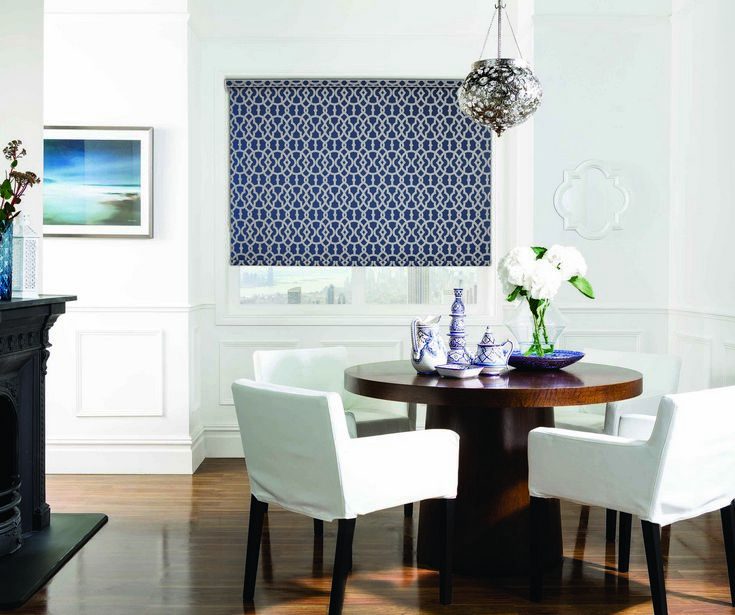 Traditional white dining area featuring patterned Roller/Holland Blinds covering the room's window. For shade and privacy.