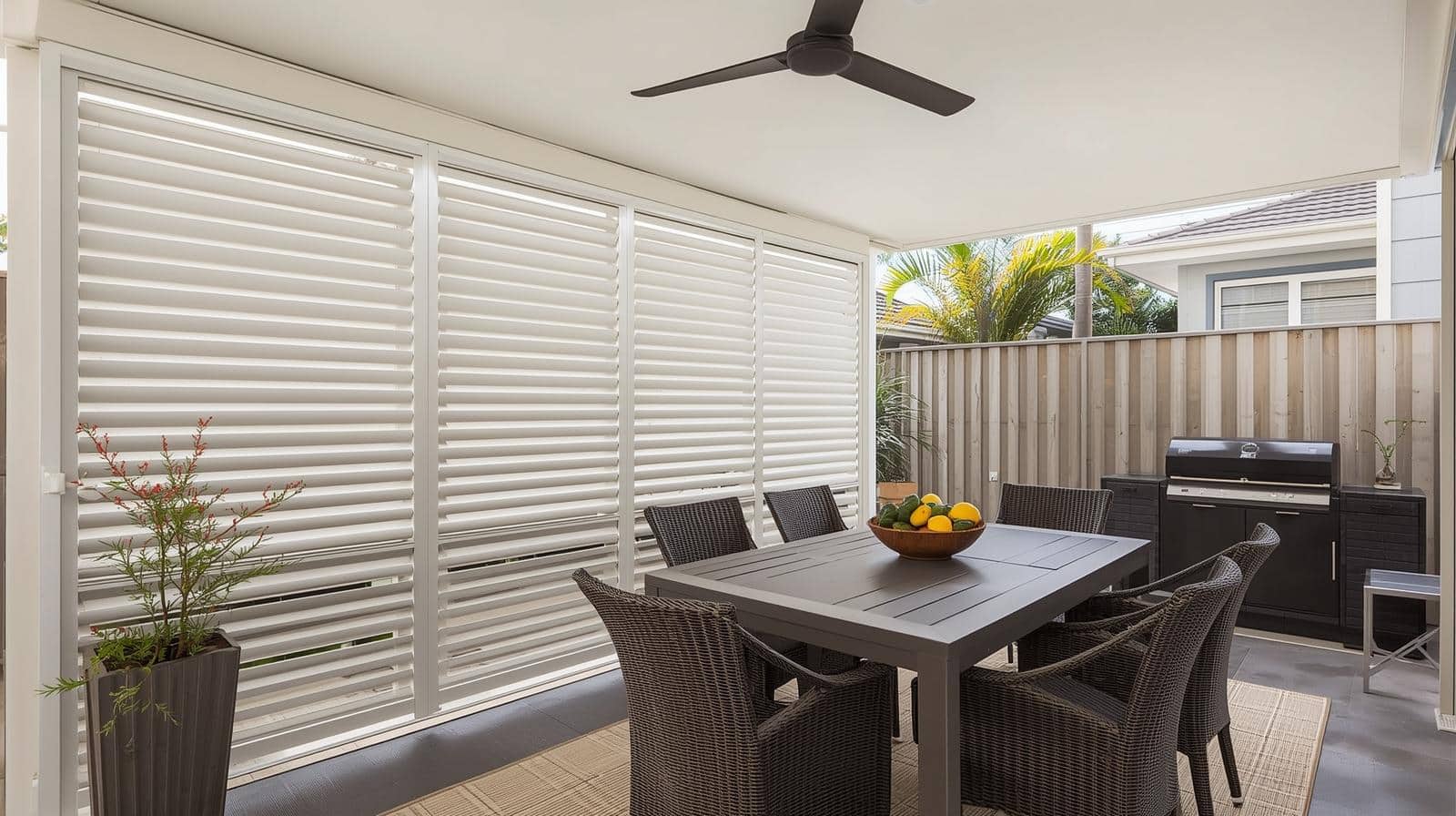 White aluminium plantation shutters on Brisbane patio providing adjustable shade and airflow for outdoor dining area